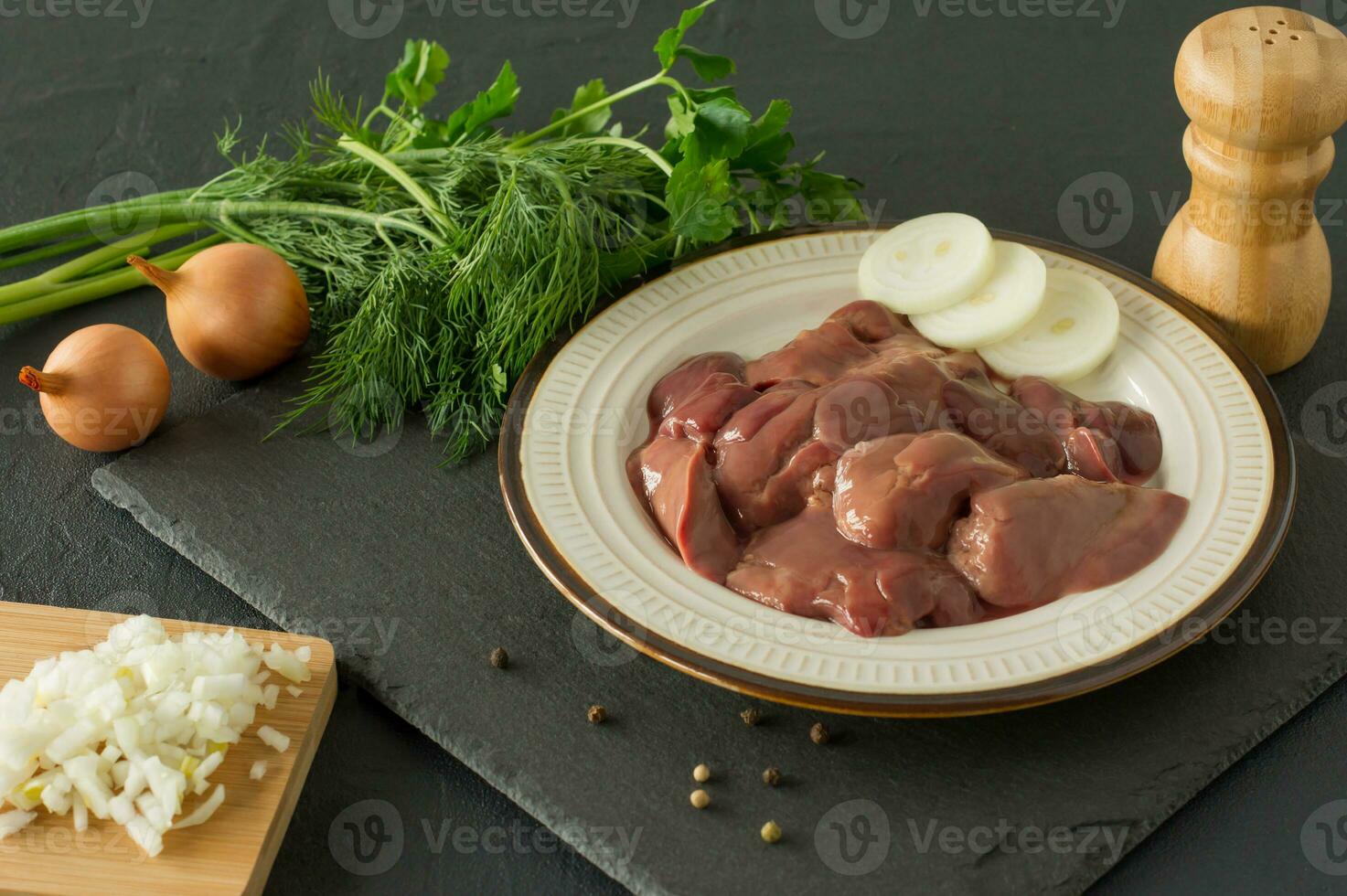 Raw chicken liver in bowl on black background. Ingredients for cooking photo