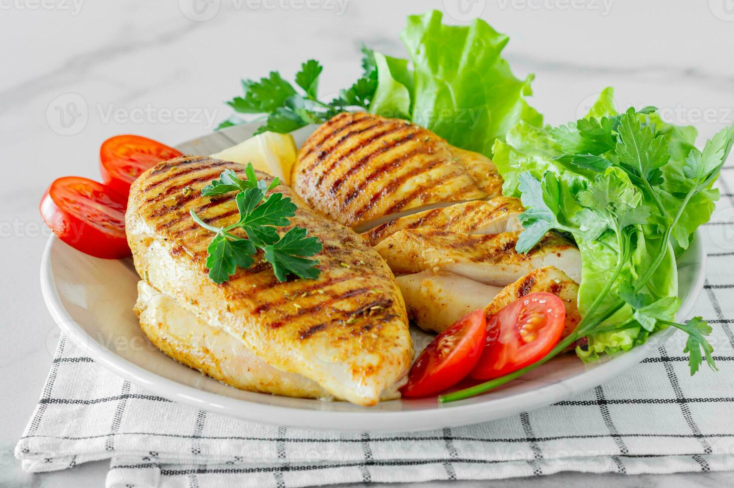 Grilled chicken breasts served on a plate with salad and vegetables. Dietary food photo