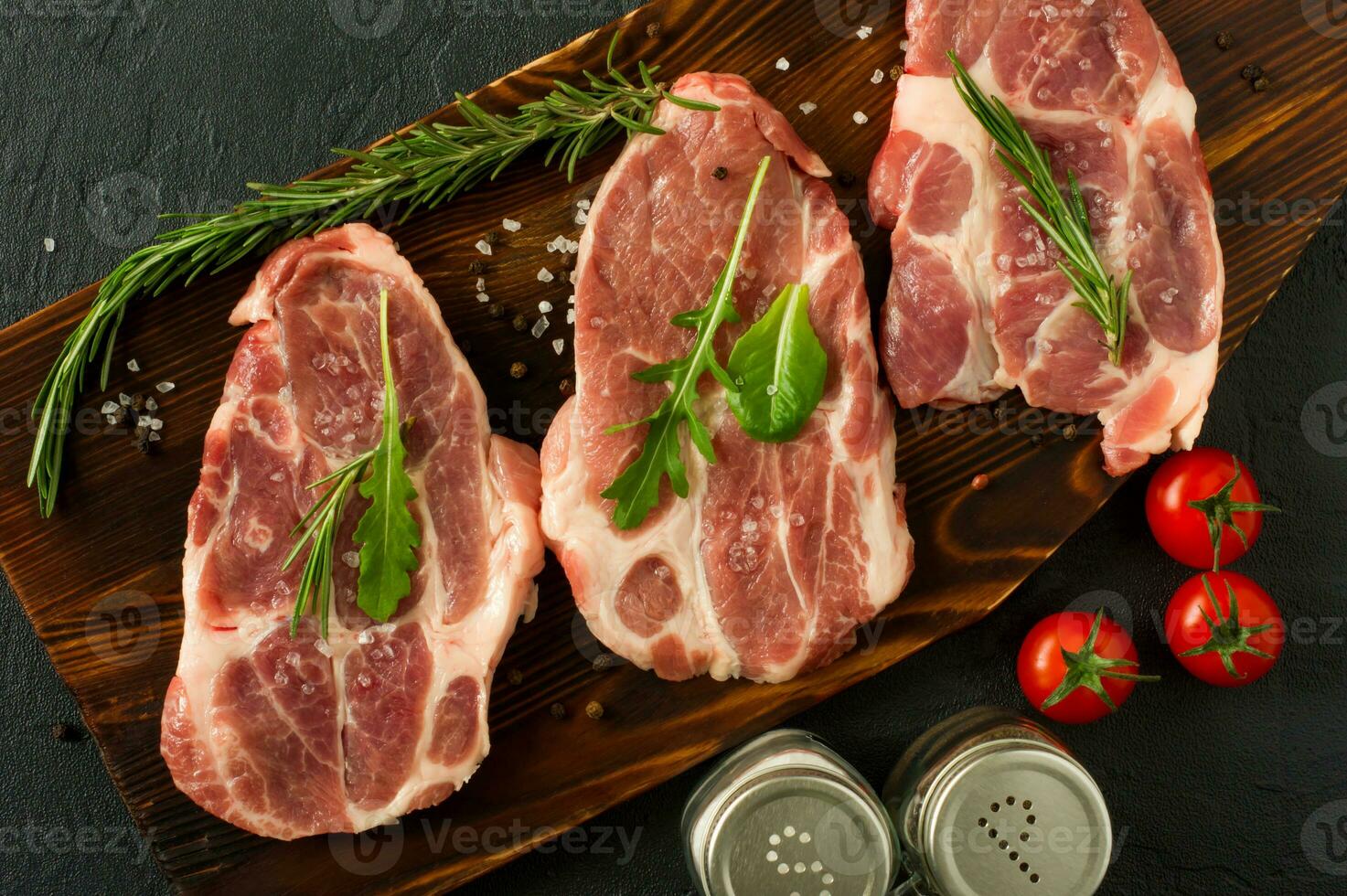 Pork neck raw meat for fresh Chop steaks on wooden cutting board. Top view. photo