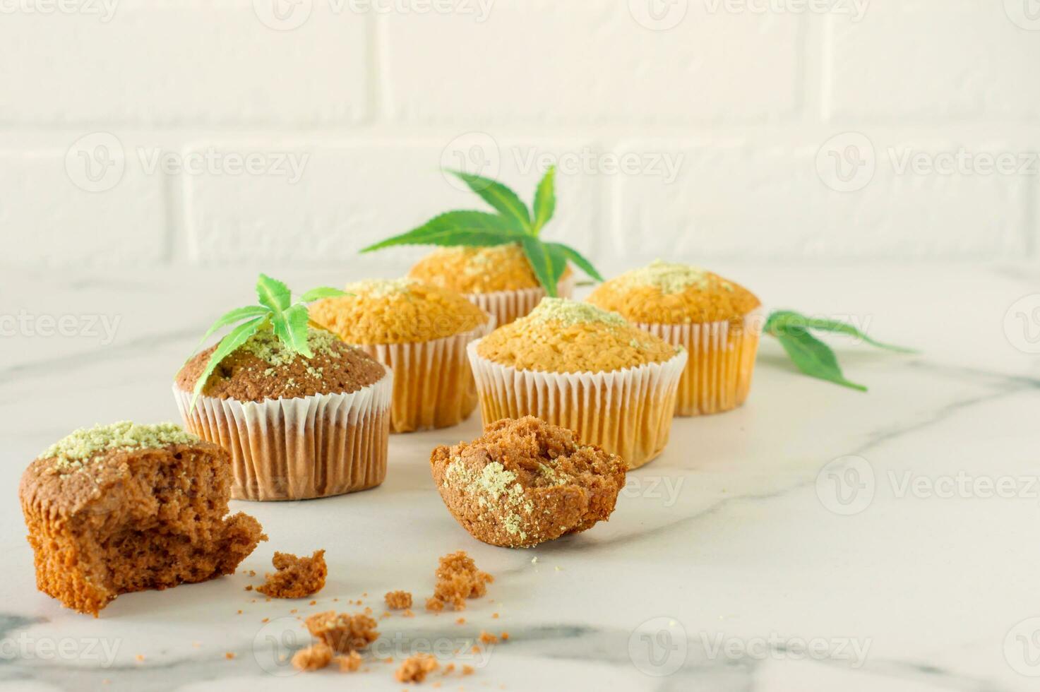 Marijuana cupcake muffins and cannabis leaves on a white marble table. Home cooked photo