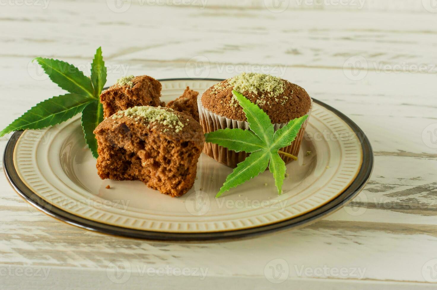 Healthy and tasty vegan and gluten free muffins in a row topped with hemp seeds on a marble table. Marijuana cupcake muffins with cannabis leaves photo