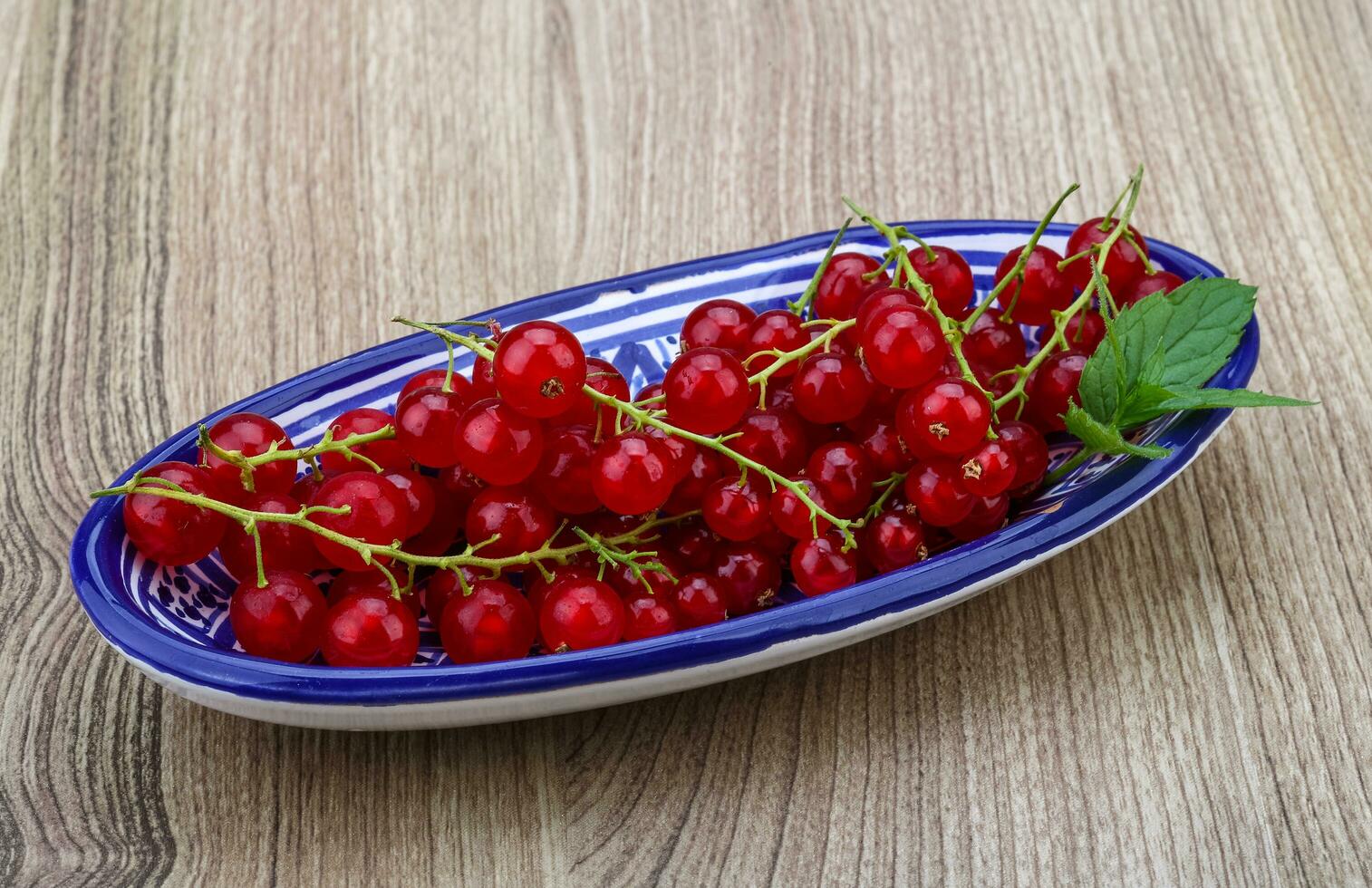 Red currants in a bowl on wooden background photo