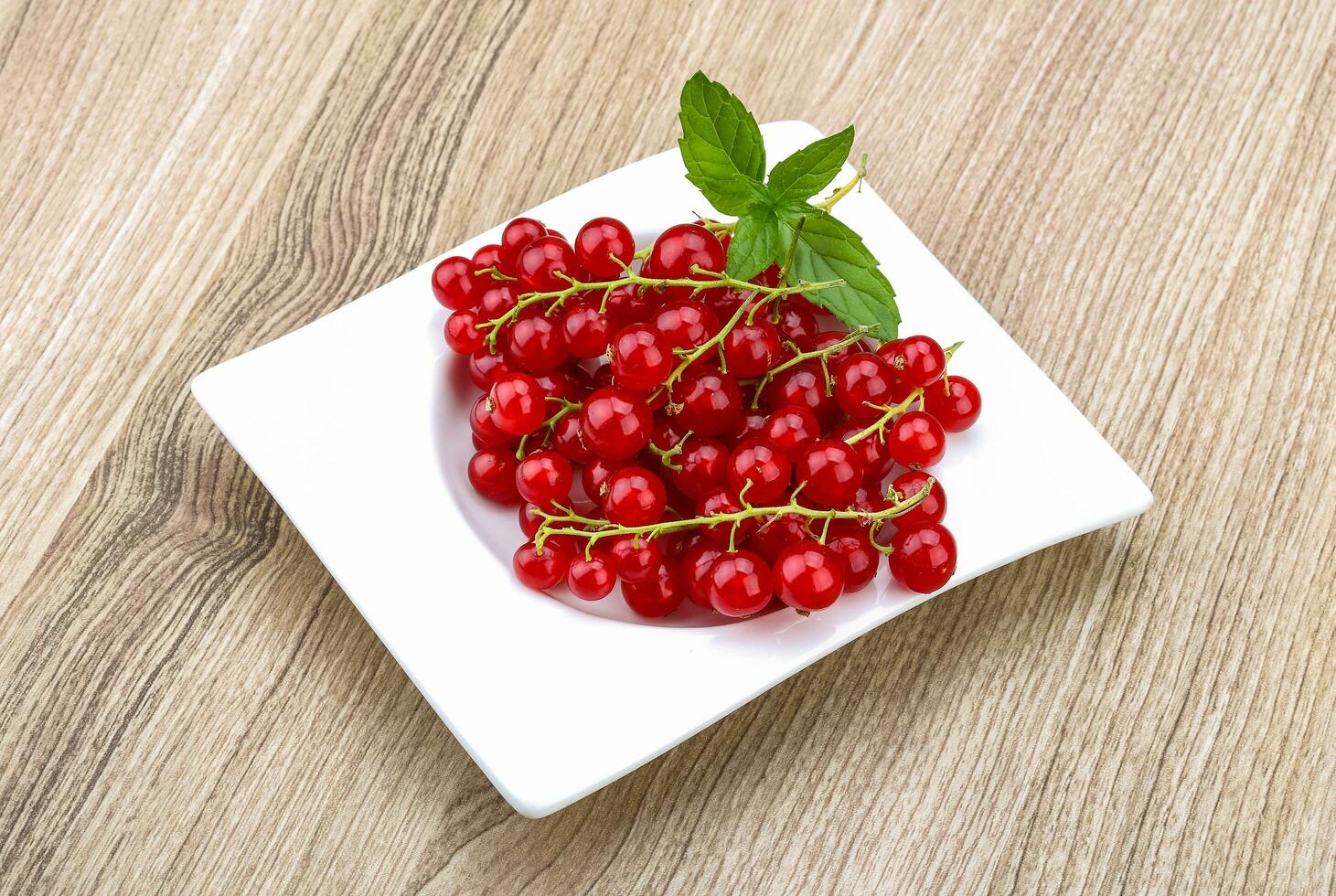 Red currants in a bowl on wooden background photo