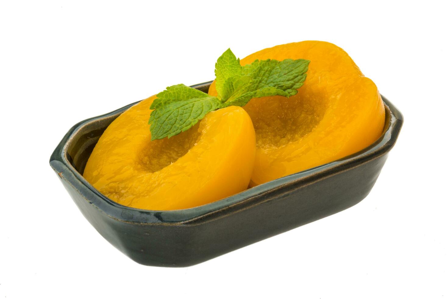 Marinated peaches in a bowl on white background photo