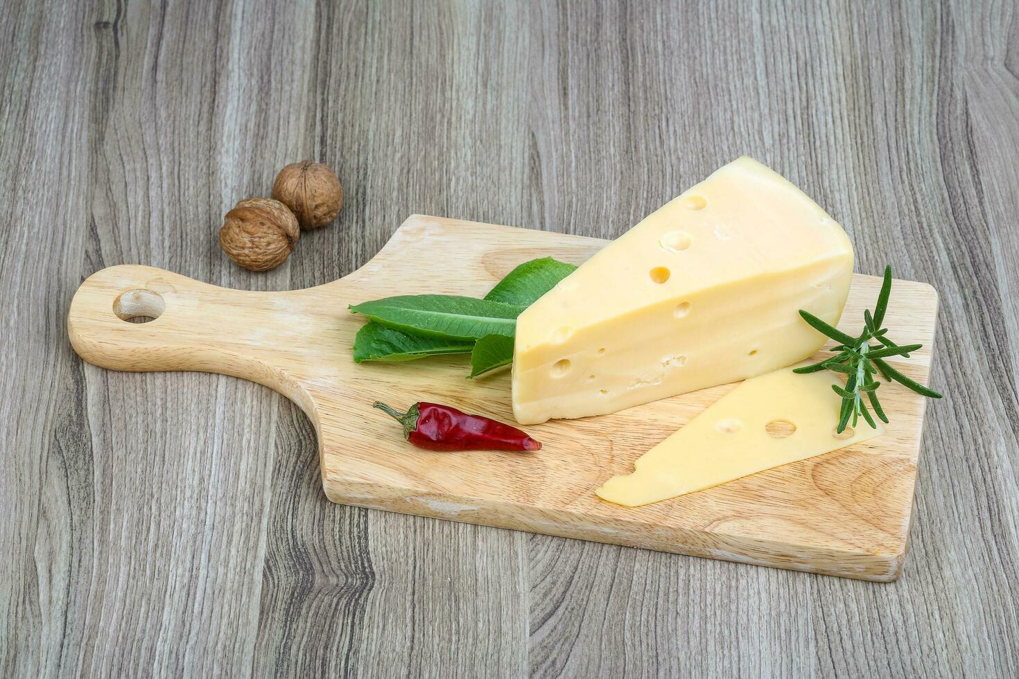 Yellow cheese on wooden board and wooden background photo