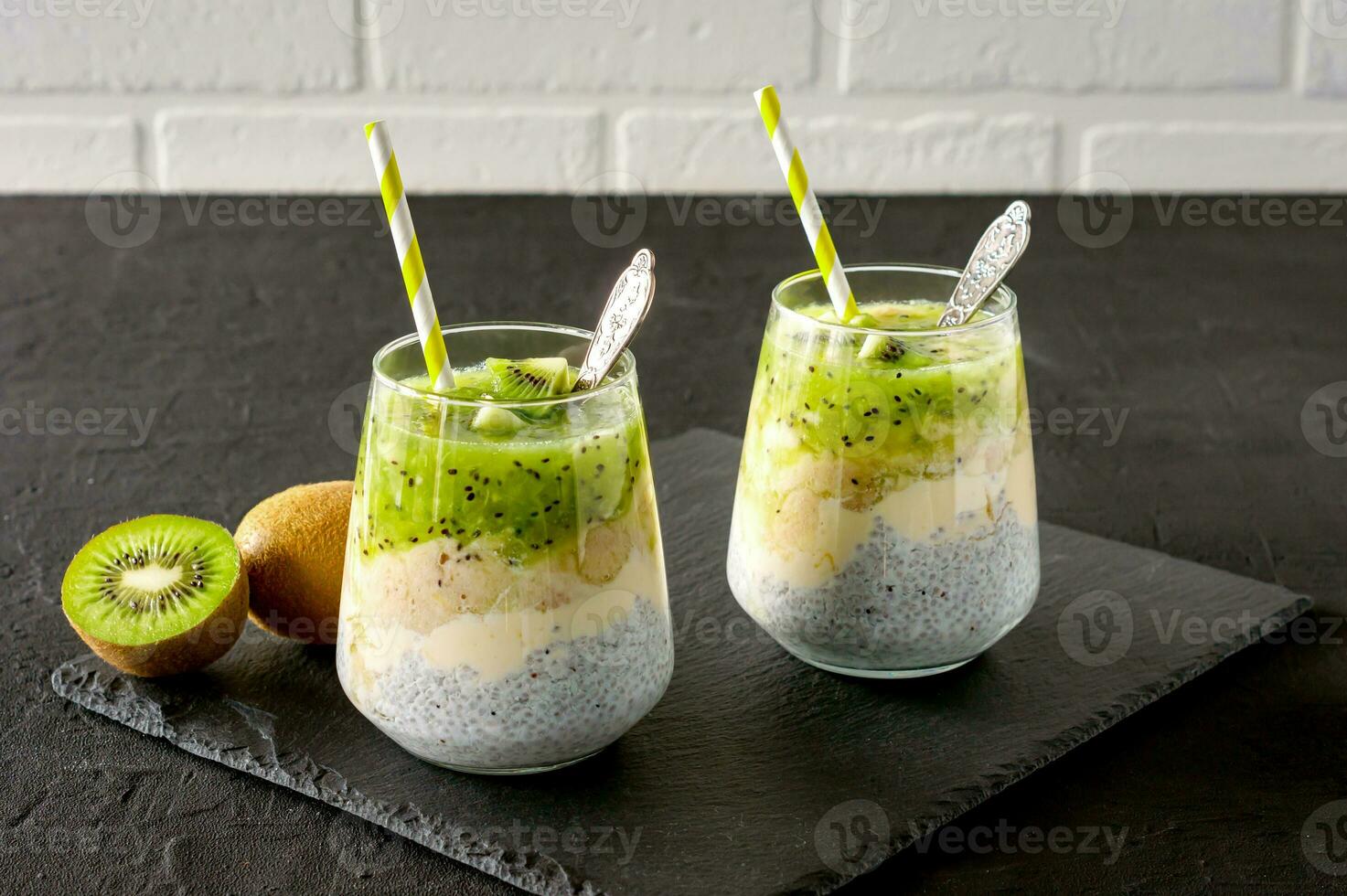 Chia seed pudding with kiwi, banana and mango. Health detox breakfast in glasses on black stone background photo