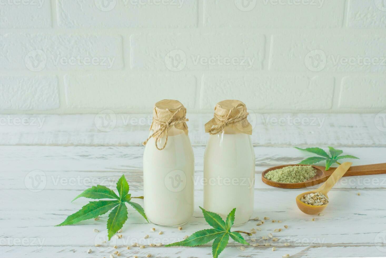 Bottles with Cannabis herbal vegan gluten and lactose free milk and cannabis leaves on wooden table photo