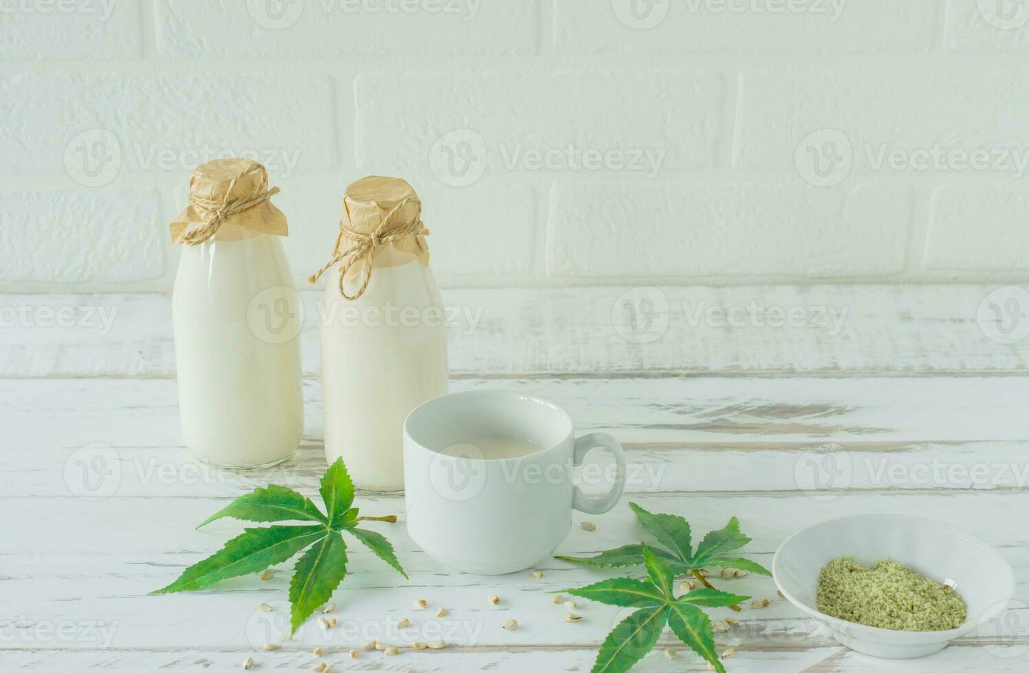 Bottles with Cannabis herbal vegan gluten and lactose free milk and cannabis leaves on wooden table photo