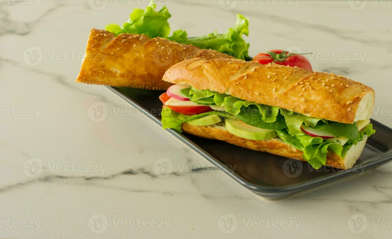 Sándwich vegano de baguette larga integral con lechuga, aguacate, tomate y queso. merienda saludable y comida para llevar foto