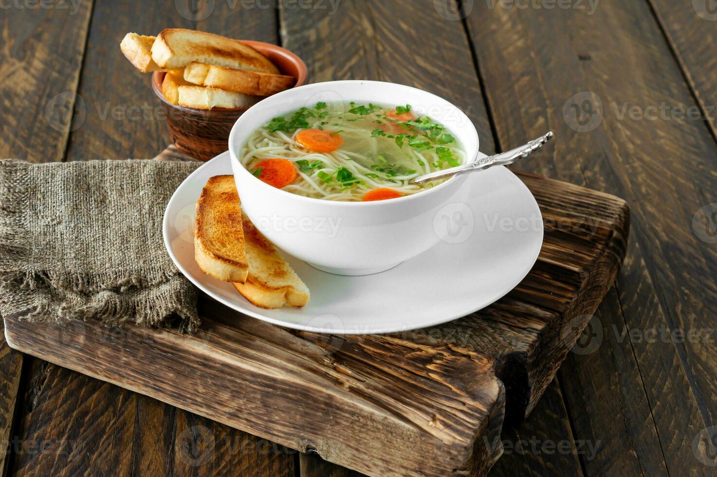 Chicken soup with vegetables in white bowl. Tasty homemade broth on a wooden background photo