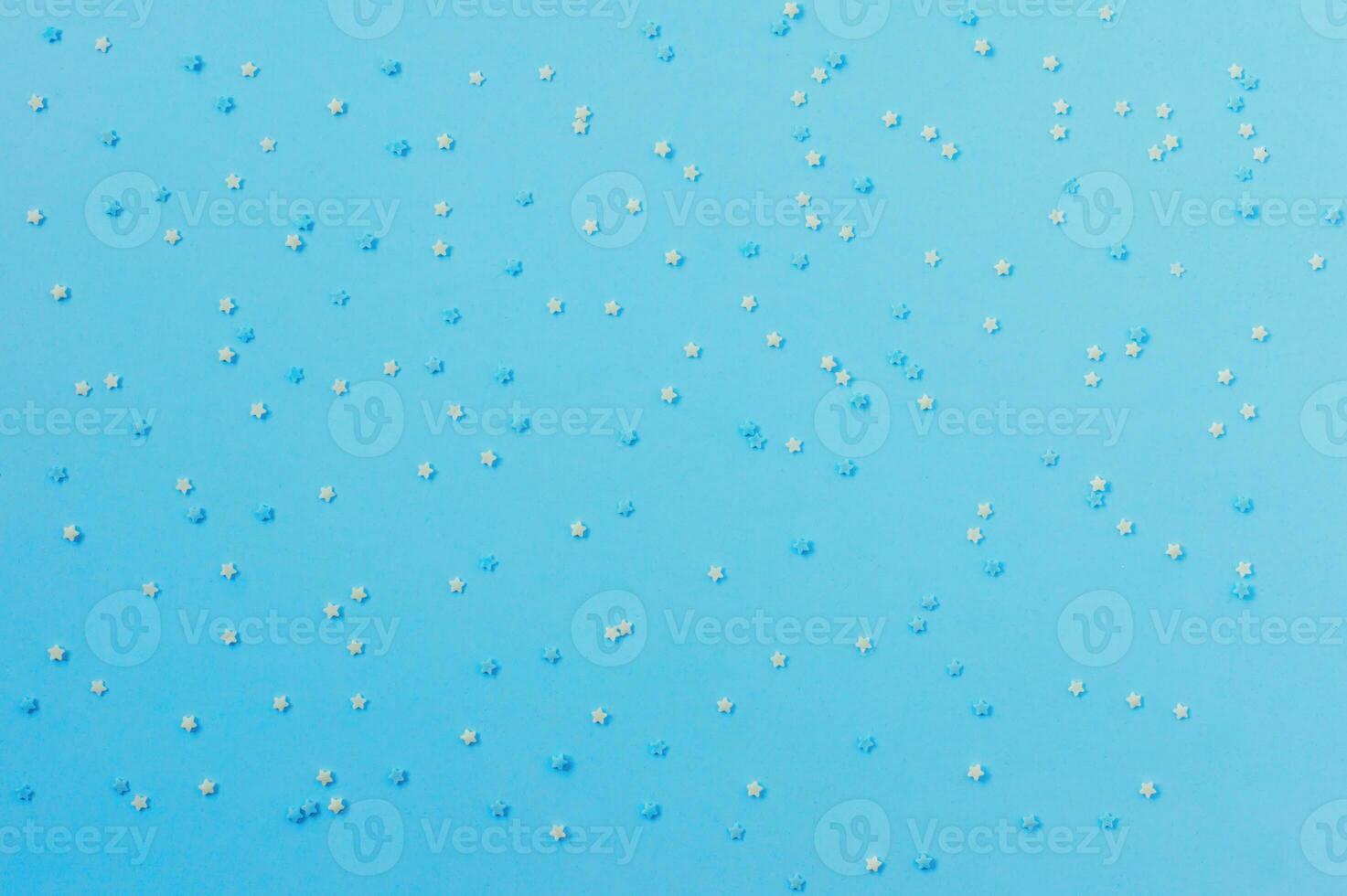 sugar sprinkles in the form of stars on blue background, congectionary decoration. copy space for text photo