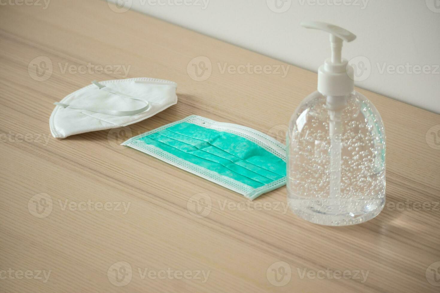 mascarilla médica con gel desinfectante de alcohol lavado a mano en mesa de madera para el concepto de prevención del coronavirus covid-19 foto