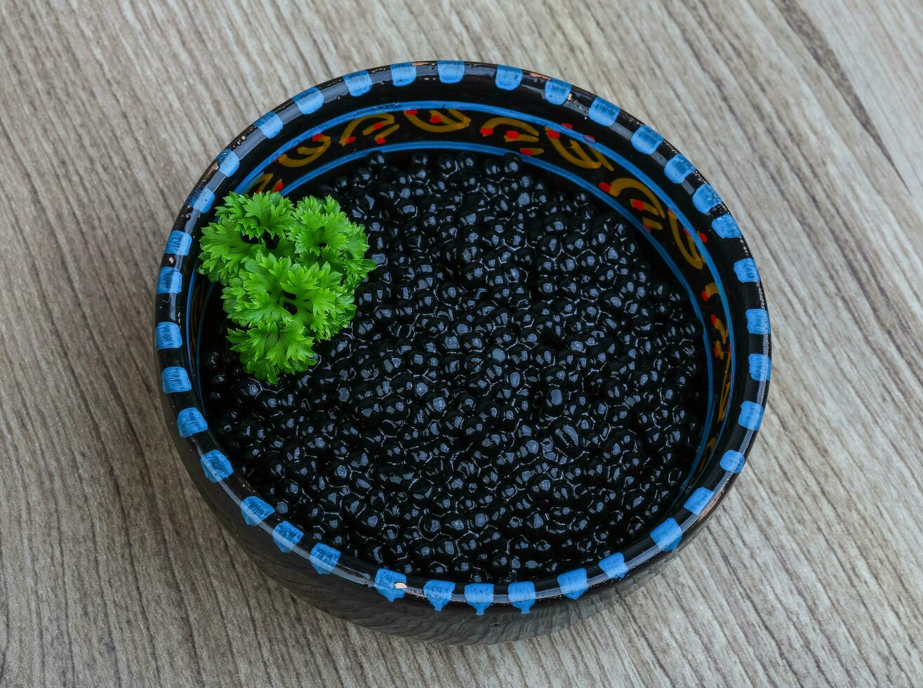 Black caviar in a bowl on wooden background photo