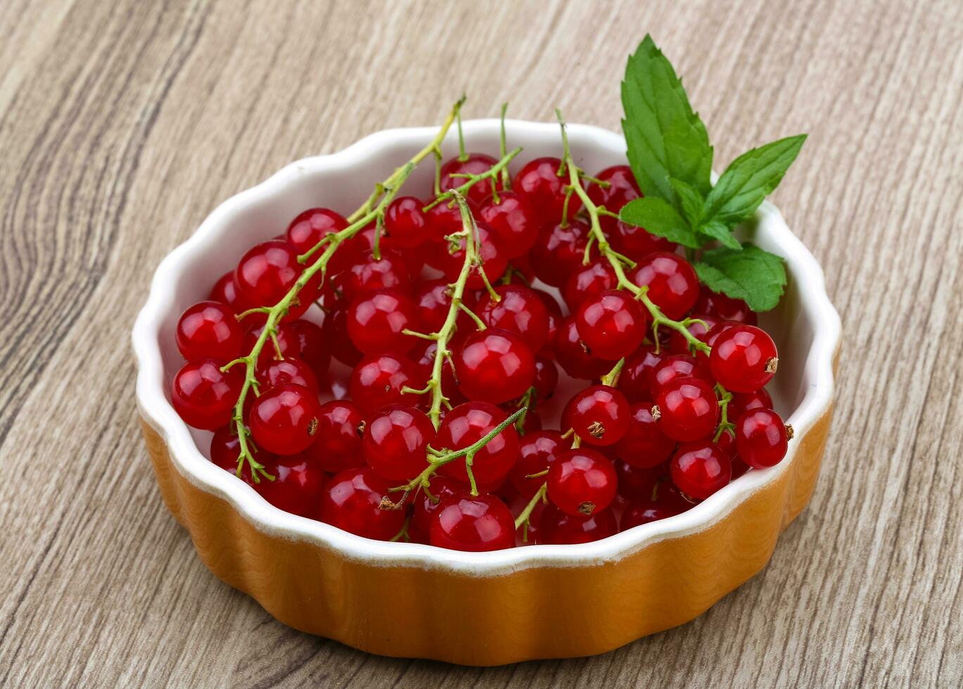 Red currant in a bowl on wooden background photo