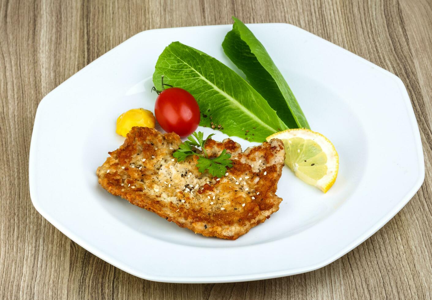 Pork schnitzel on the plate and wooden background photo