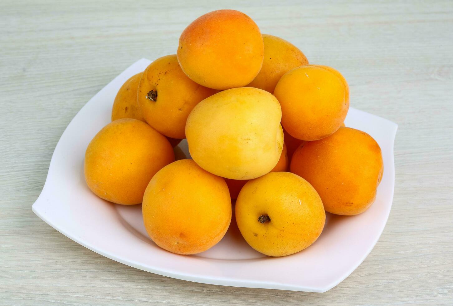 Apricots on the plate and wooden background photo