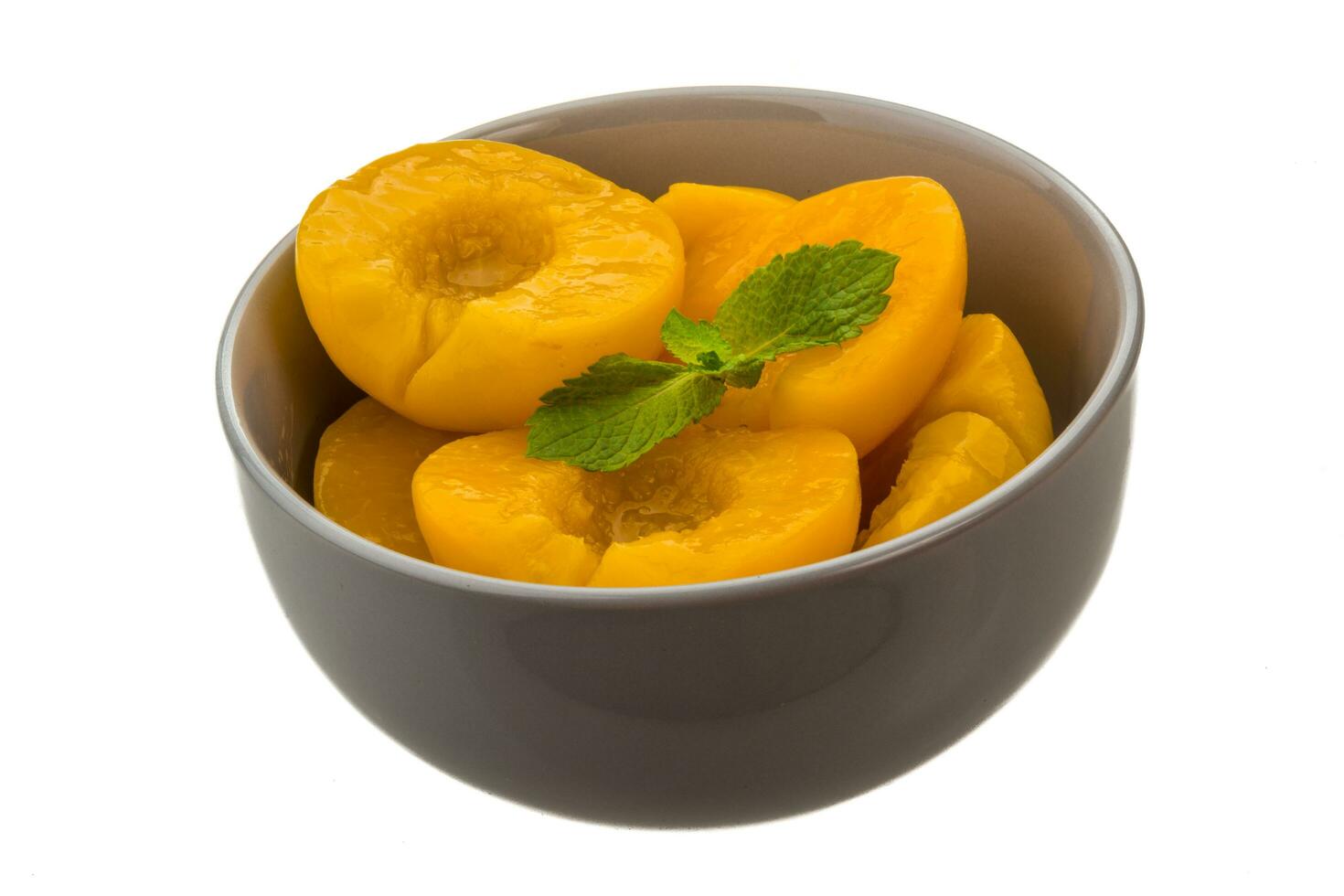 Marinated peaches in a bowl on white background photo