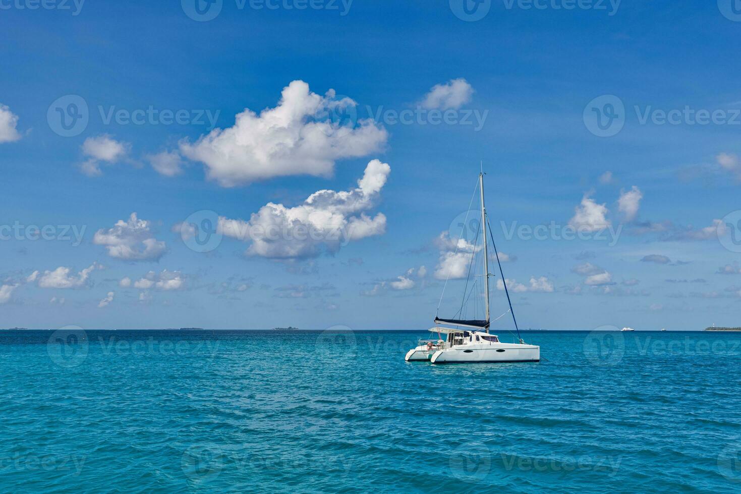 Luxury yacht in open waters with beautiful clouds. Catamaran white sailboat in tropical ocean lagoon, sea horizon under sunny skyline. Idyllic outdoor sport and travel recreation landscape, seascape photo