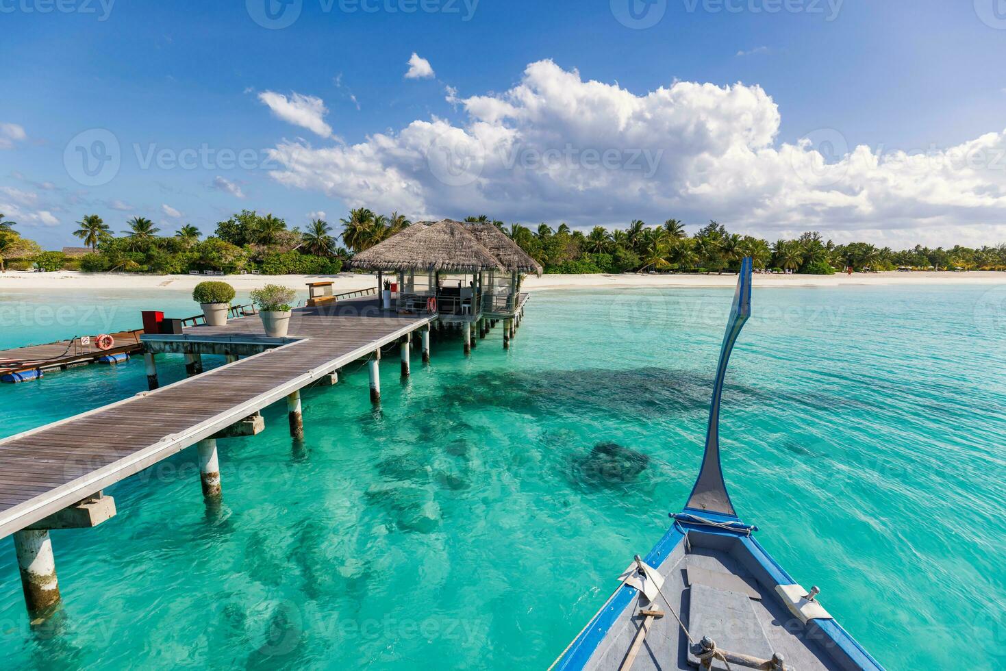 perfecta isla paraíso playa maldivas, viajes. embarcadero largo y un barco dhoni tradicional en el muelle con palmeras, isla de maldivas. hermoso paisaje tropical panorámico con un océano turquesa soleado. foto