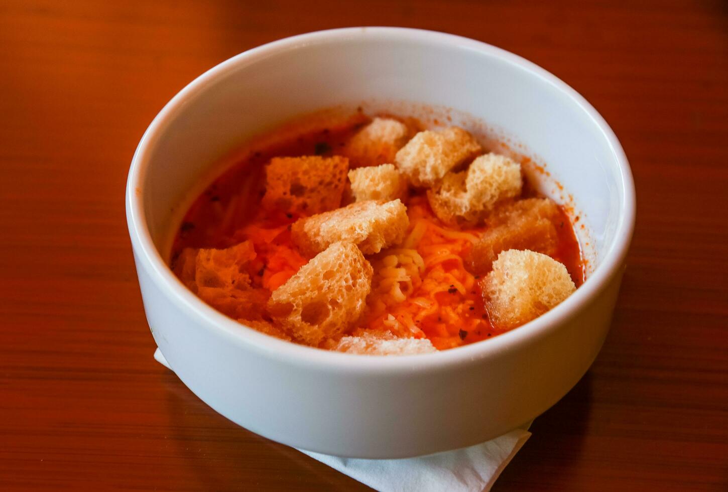 Tomato soup in a bowl on wooden background photo