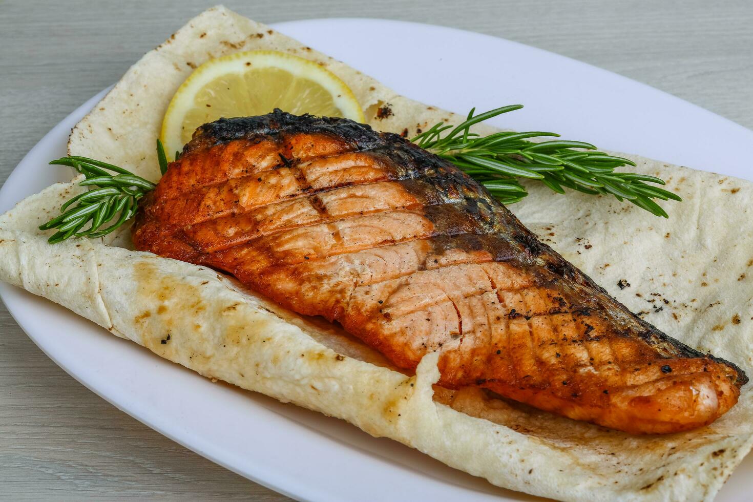 Grilled salmon on the plate and wooden background photo