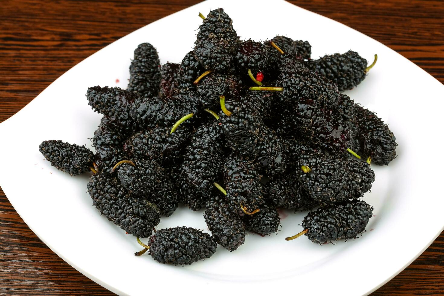 Mulberry on the plate and wooden background photo