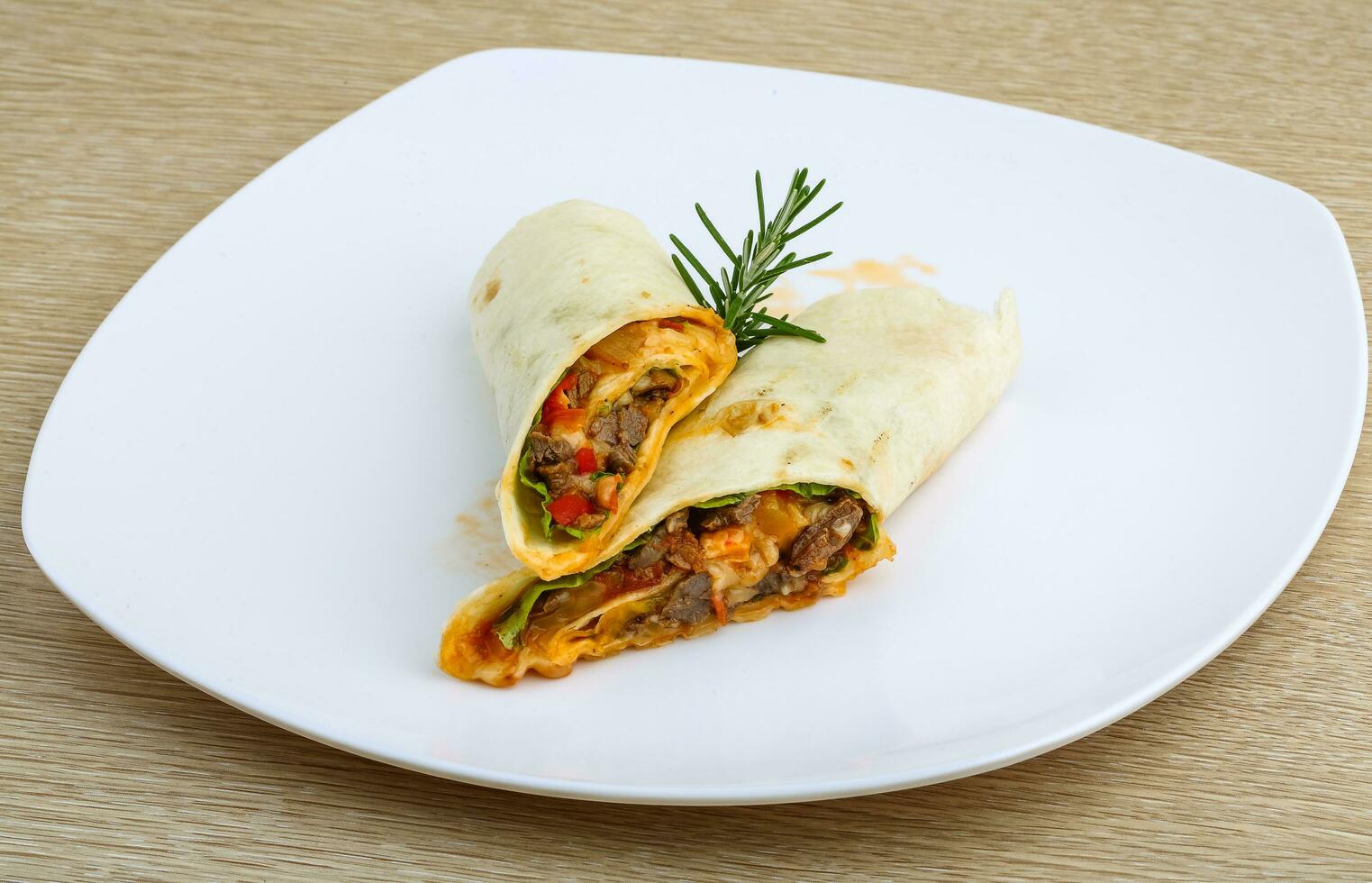 envuelva la tortilla en el plato y el fondo de madera foto