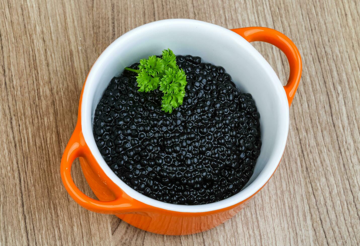 Black caviar in a bowl on wooden background photo