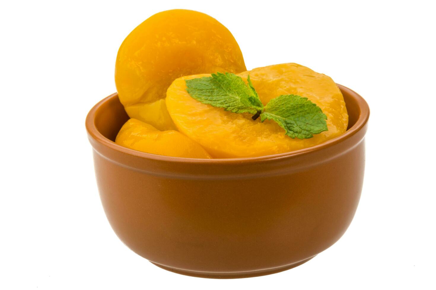 Marinated peaches in a bowl on white background photo