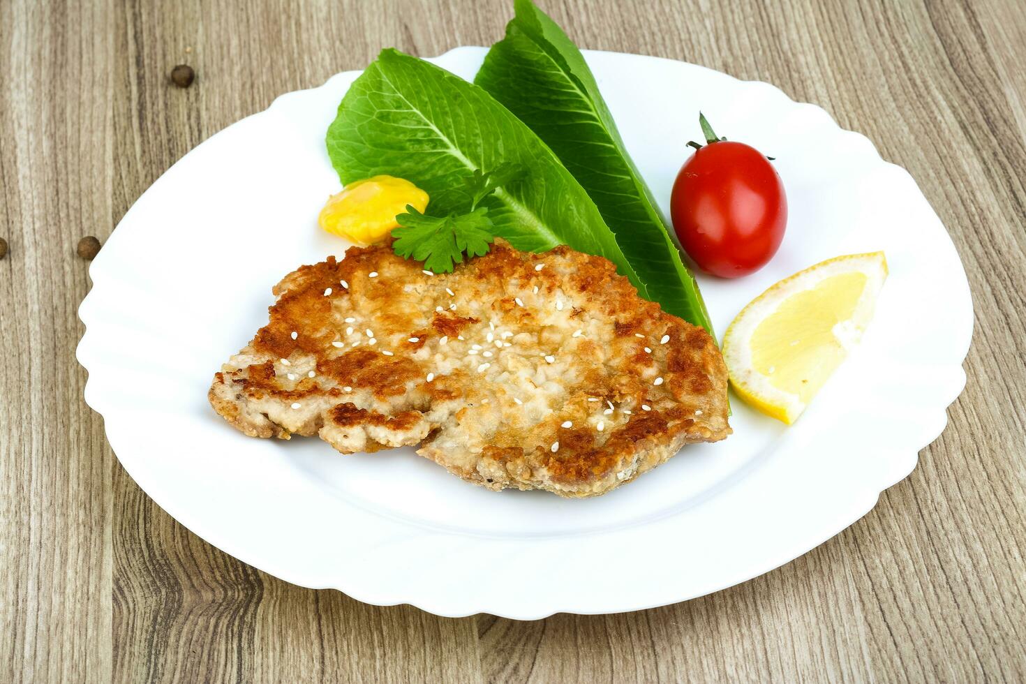 Pork schnitzel on the plate and wooden background photo