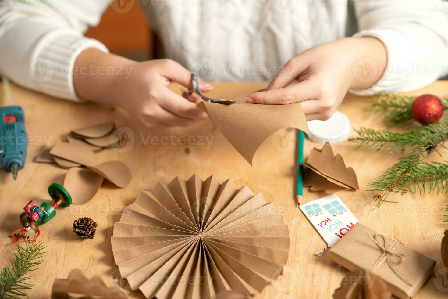 la niña hace decoraciones para árboles de navidad con papel con sus propias manos. paso 2 foto