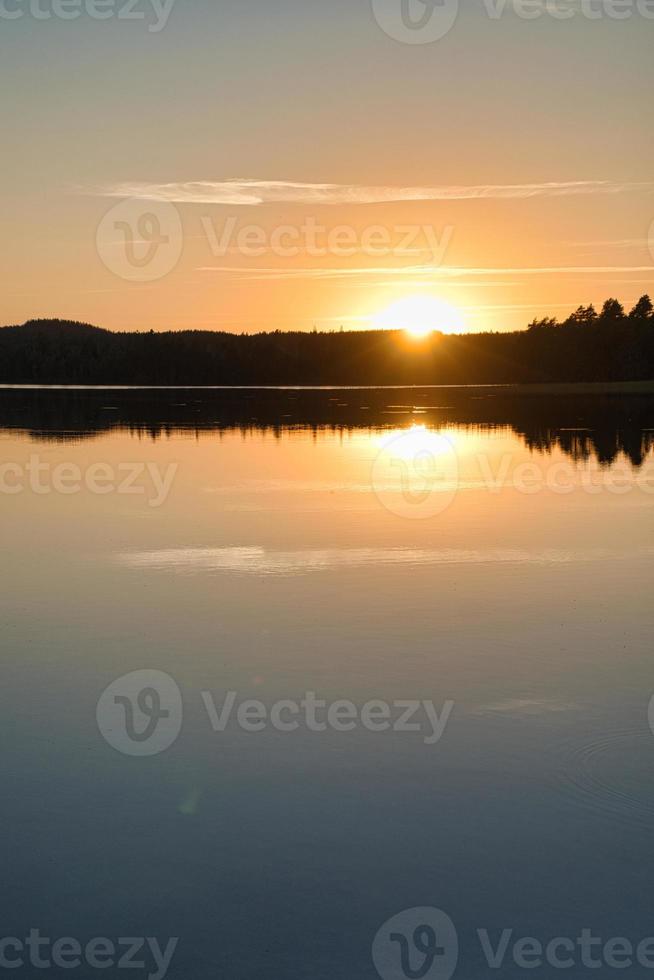 Sunset with reflection on a Swedish lake in Smalland. Romantic evening mood photo