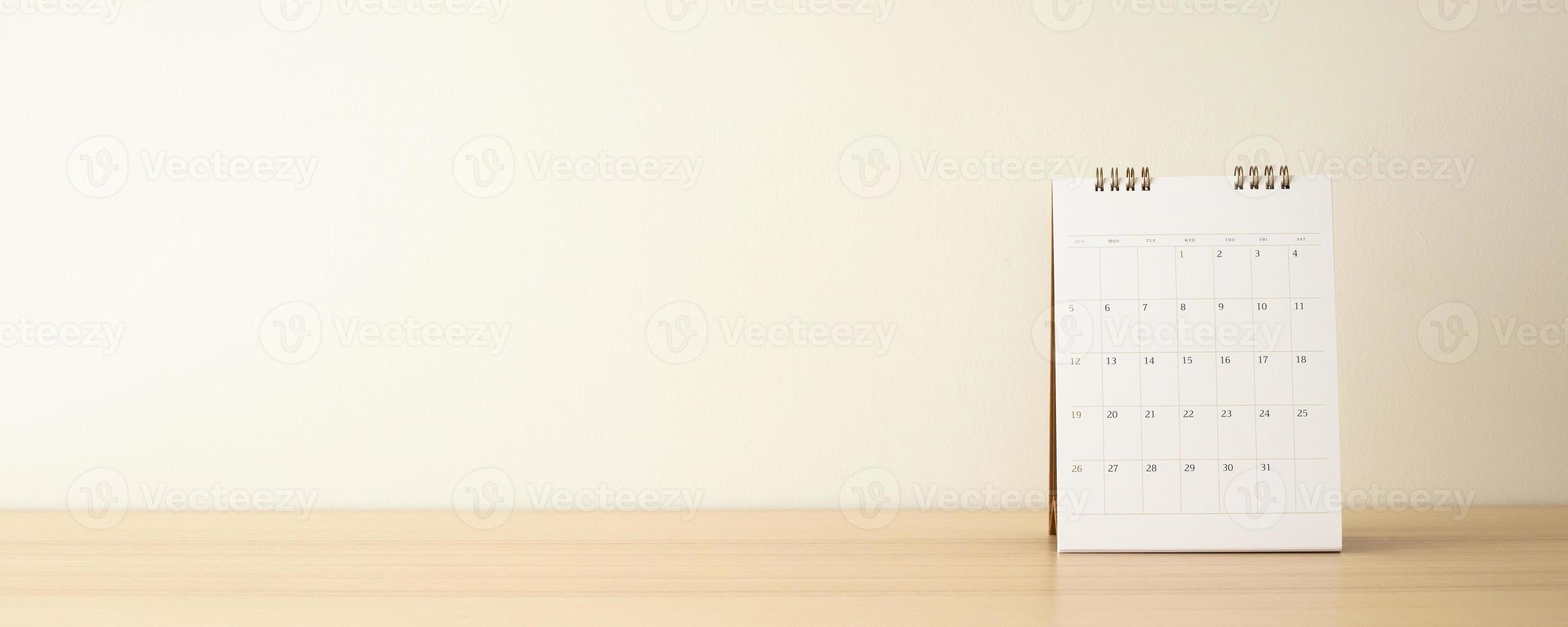 Calendar page close up on wood table with white wall background business planning appointment meeting concept photo