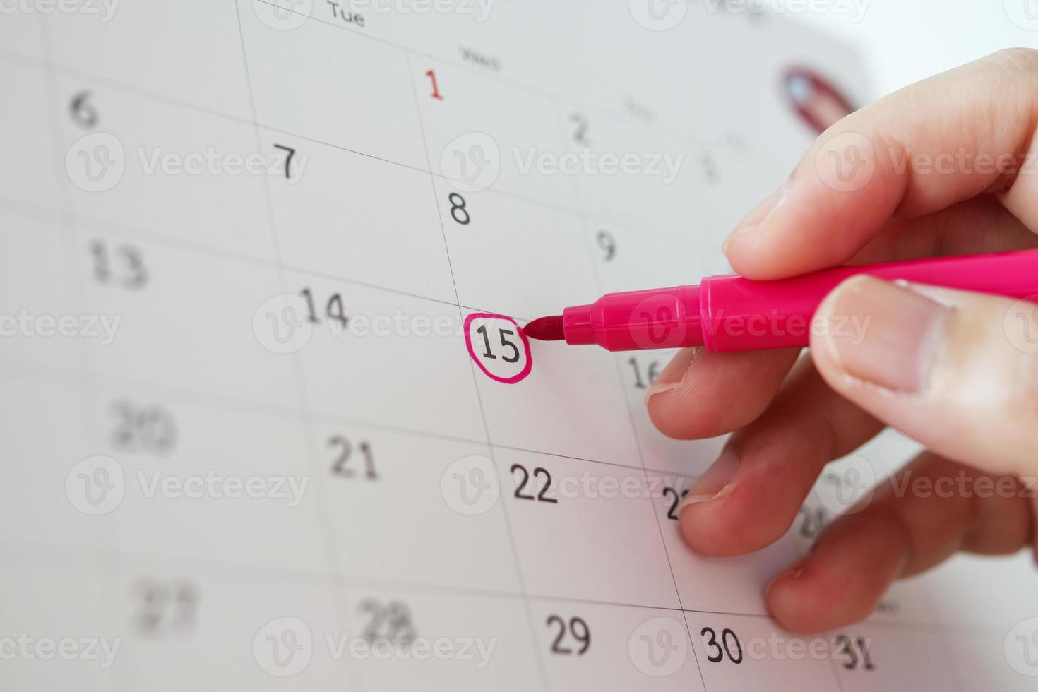 Hand with pen mark at 15th on calendar date photo