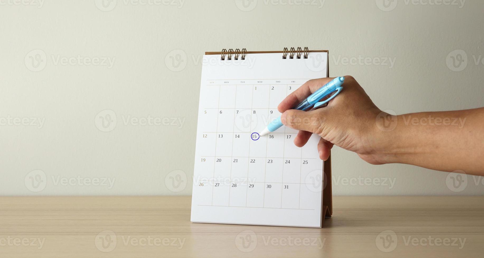 Hand with pen mark at 15th on calendar date photo