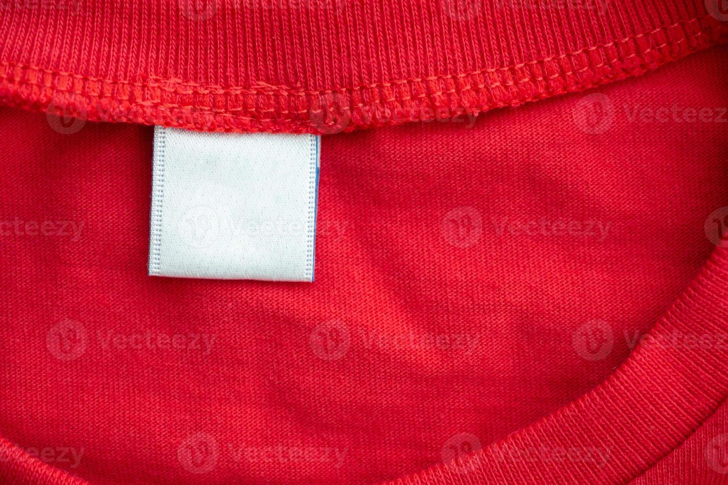 White blank clothing tag label on new red cotton shirt fabric texture background photo