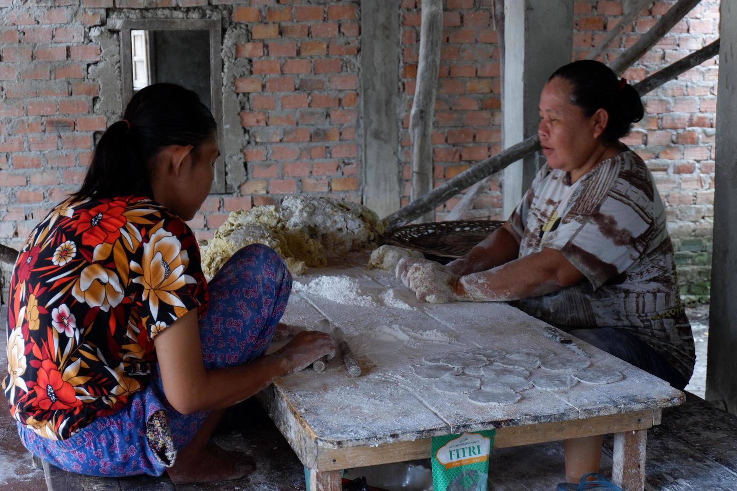 ogan ilir, indonesia - 27 de octubre de 2021, dos mujeres trabajan y hablan entre sí hacen comida tradicional foto