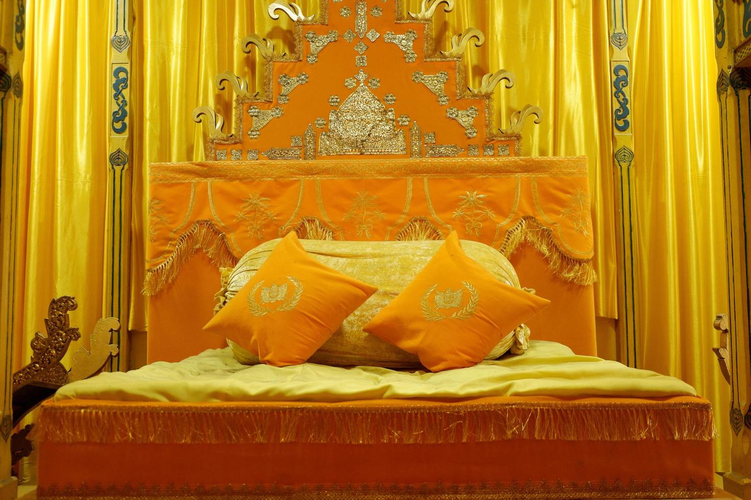 Istana Maimun, Medan North Sumatera, Indonesia - October 23, 2021, Orange bed with pillows and decorated with golden curtains photo