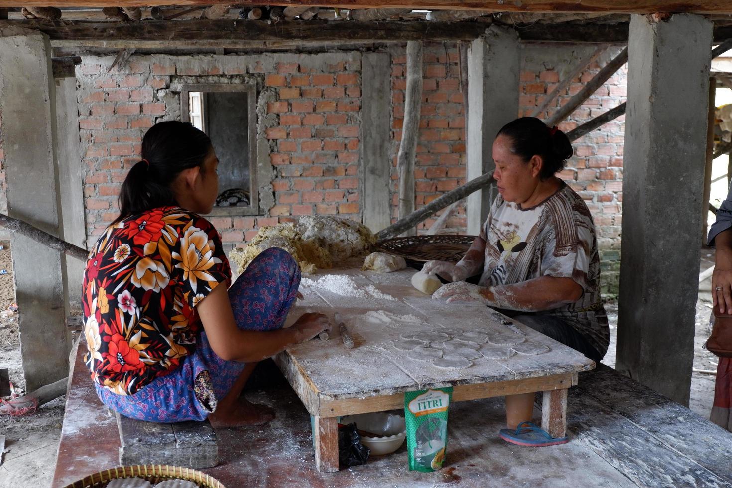 Ogan Ilir, Indonesia -October 27, 2021, Two women work and talking to each other make food traditional photo