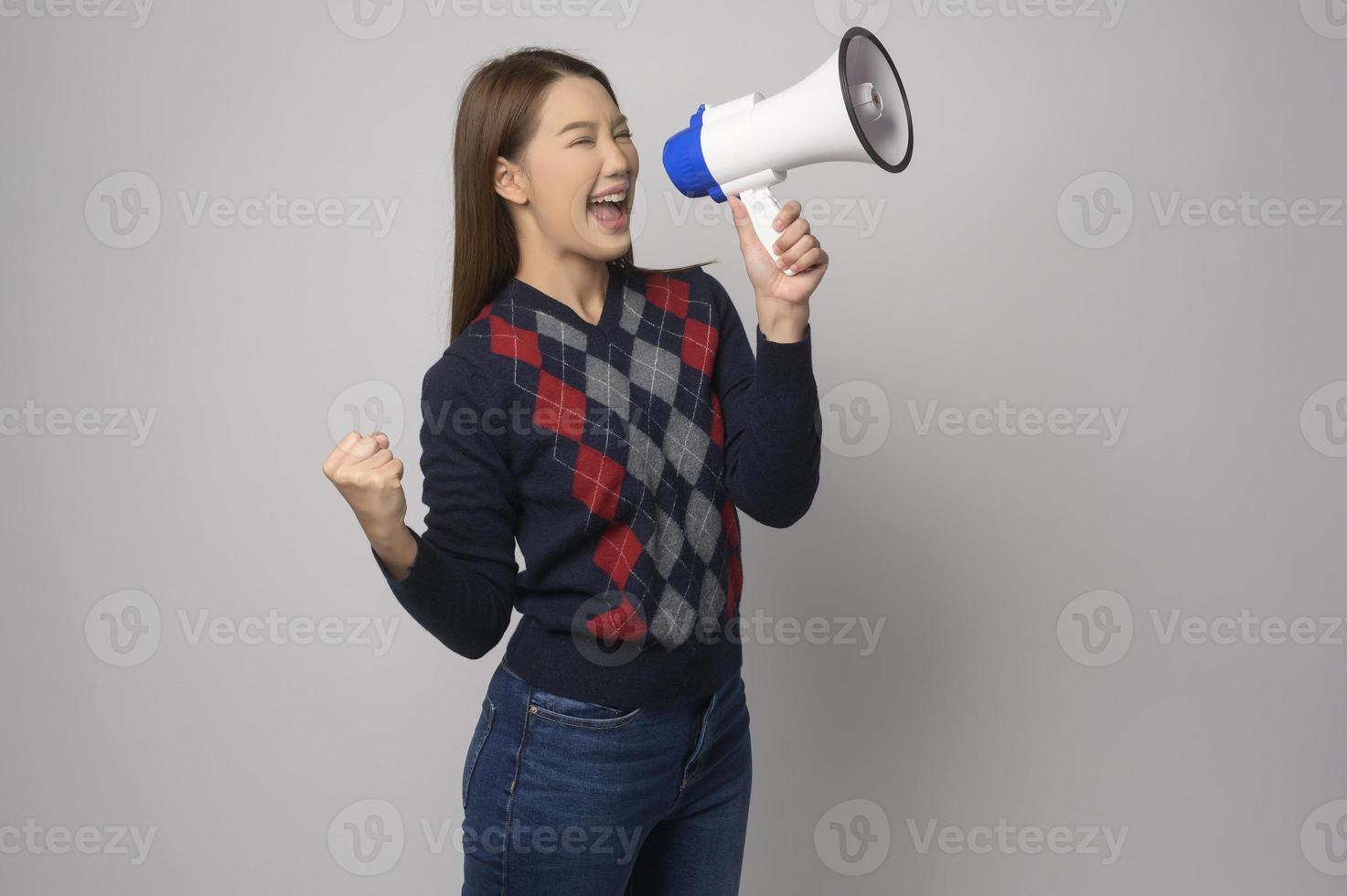 Young smiling woman holding megaphone over white background studio. photo