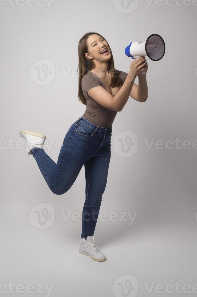 joven mujer sonriente con megáfono sobre estudio de fondo blanco. foto