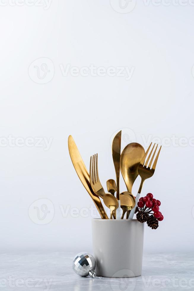 Set of cutlery of spoons, knives and forks in cup with holiday decorations on dining table, copy space photo