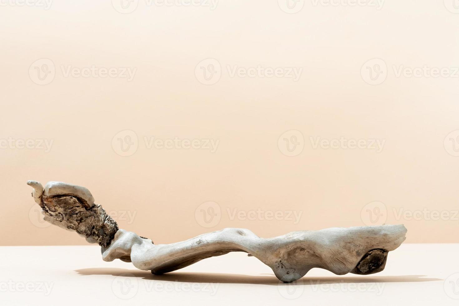 A minimalistic scene of a podium of piece of wood on beige background, for natural cosmetics photo