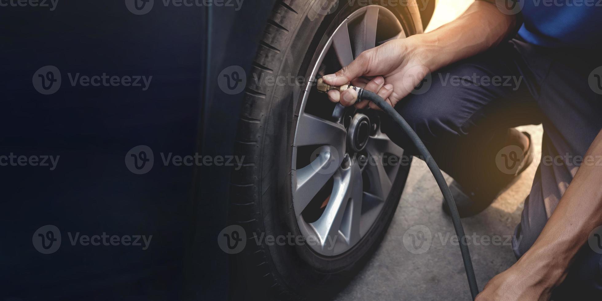Man filling Air into the Tire. Car Driver Checking Air Pressure and Maintenance his Car by himself before Traveling photo
