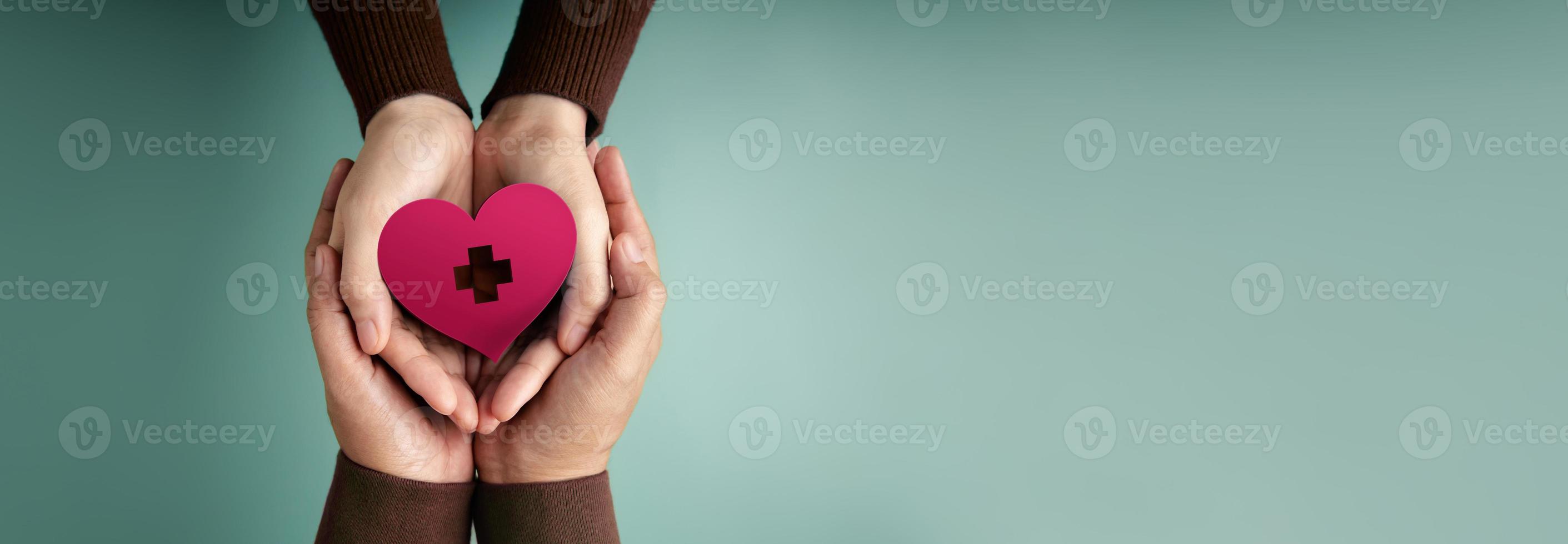 Donation Concepts. Hands of Volunteer People Embracing a Heart Shape with a Red Cross Sign Together. Love, Health Care, Donation and Charity. Top View photo