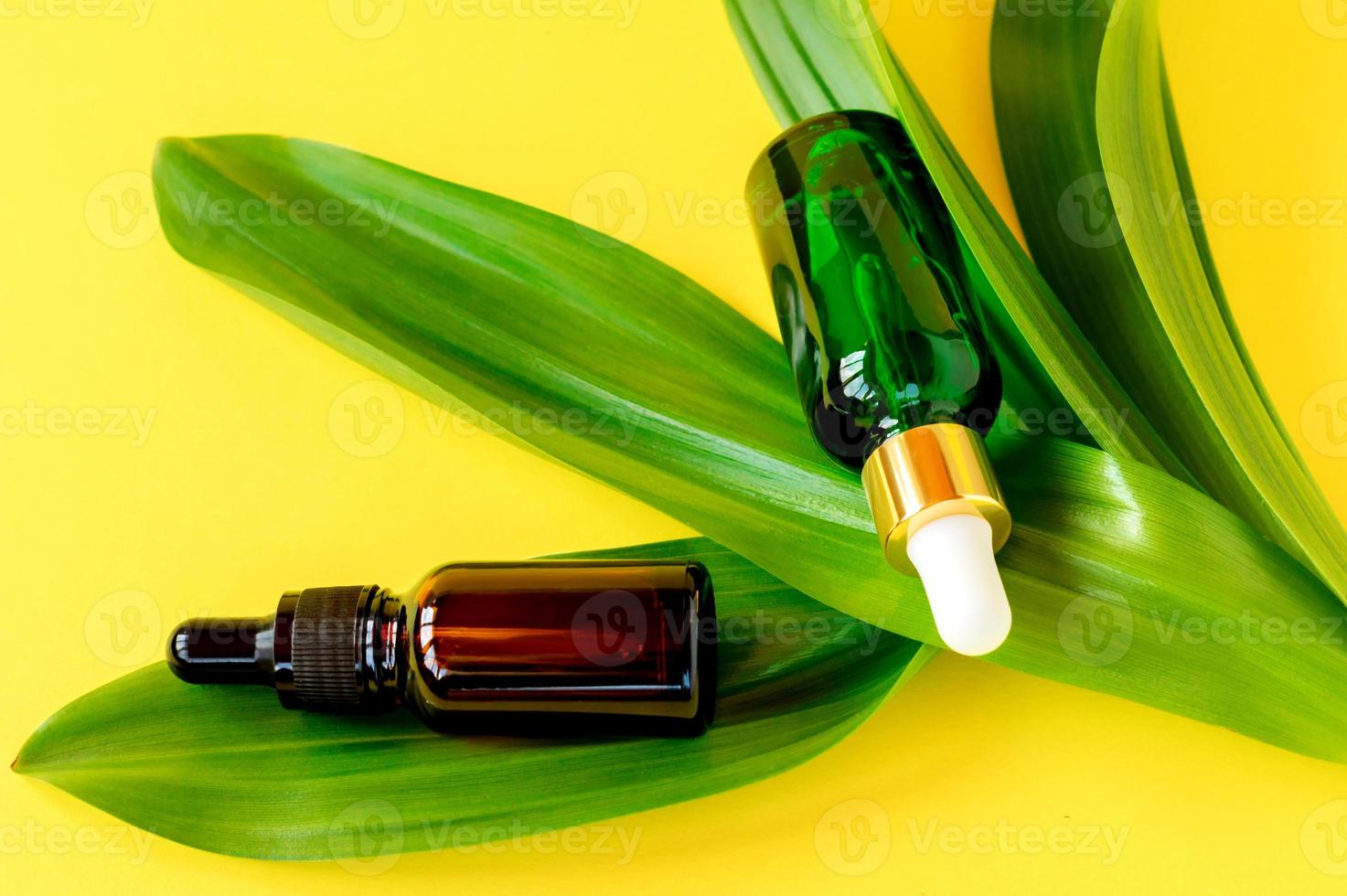 recipiente de botella natural para el cuidado de la piel y hoja verde orgánica sobre fondo amarillo. remedio casero y concepto de producto de belleza. foto