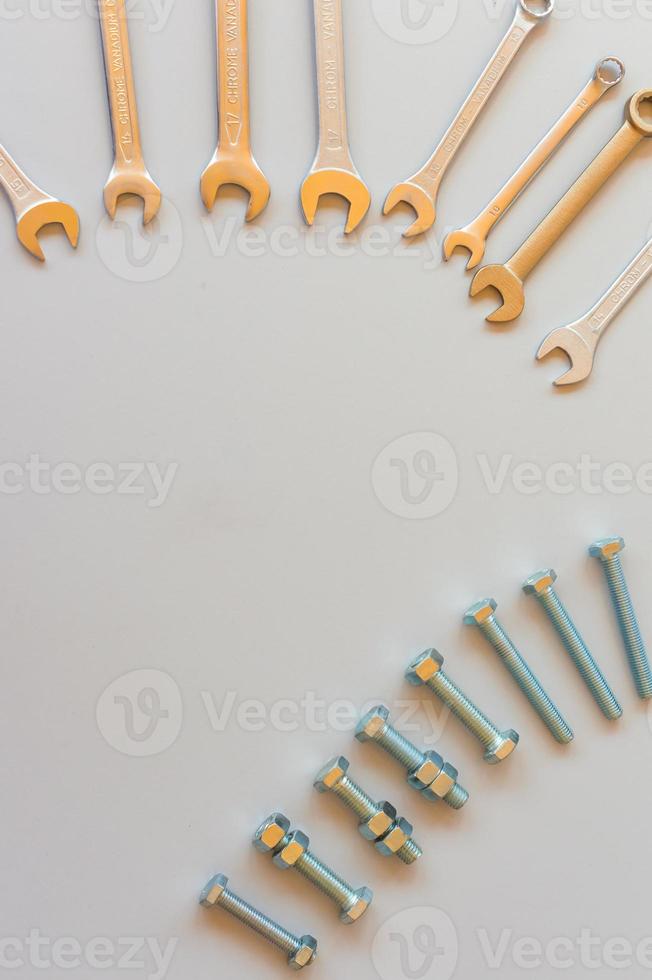 New wrenches on grey background, top view with space for text. professional plumber tools with fixing bolts. photo