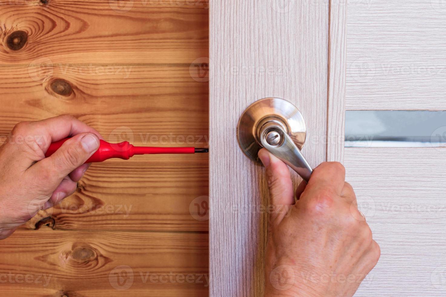 Close-up Of Man's Hand Installing Door Lock At Home photo