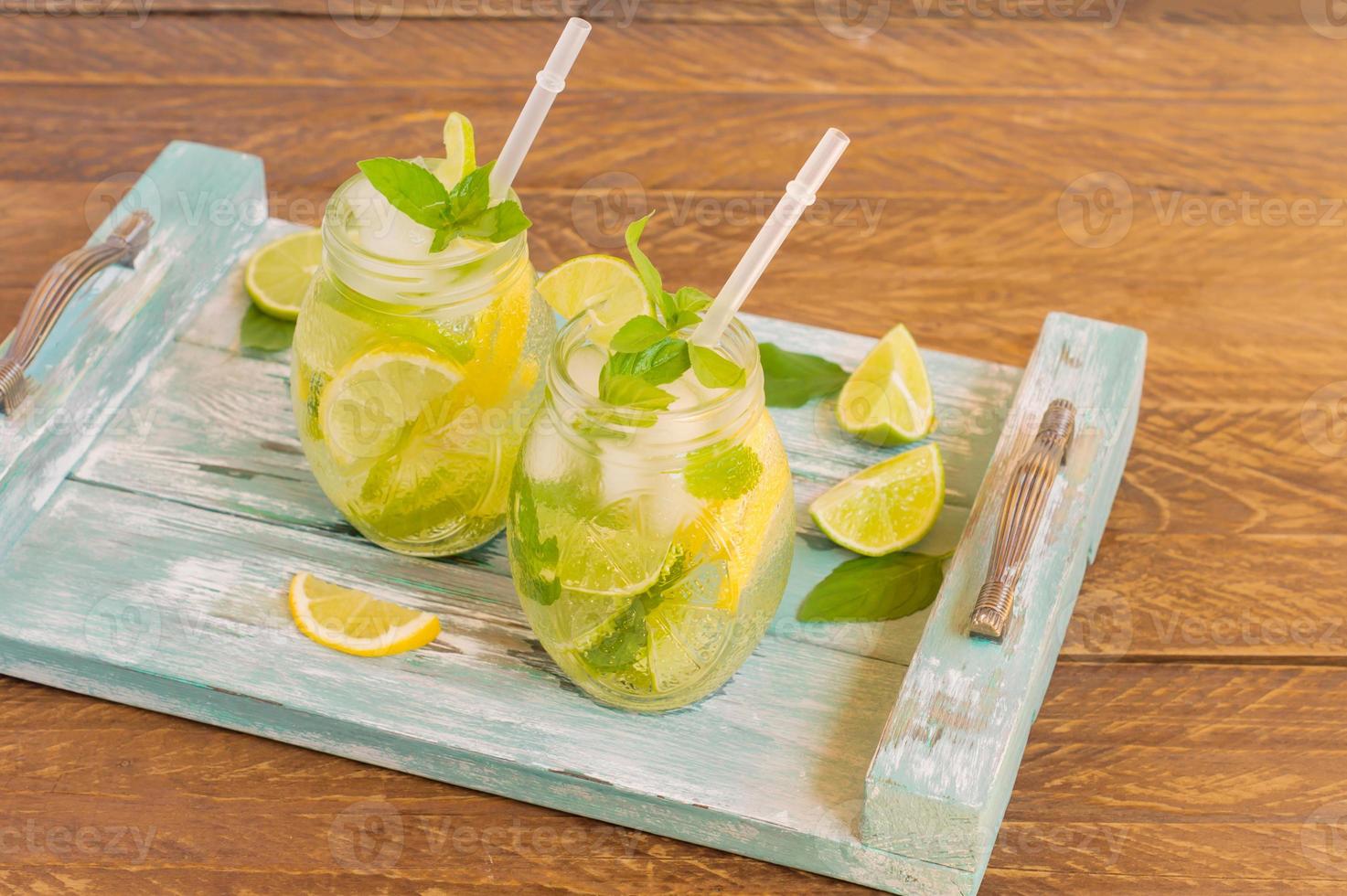 summer fresh cold lemonade with lime, lemon, mint and ice served on blue wooden tray. Non-alcoholic beverage photo