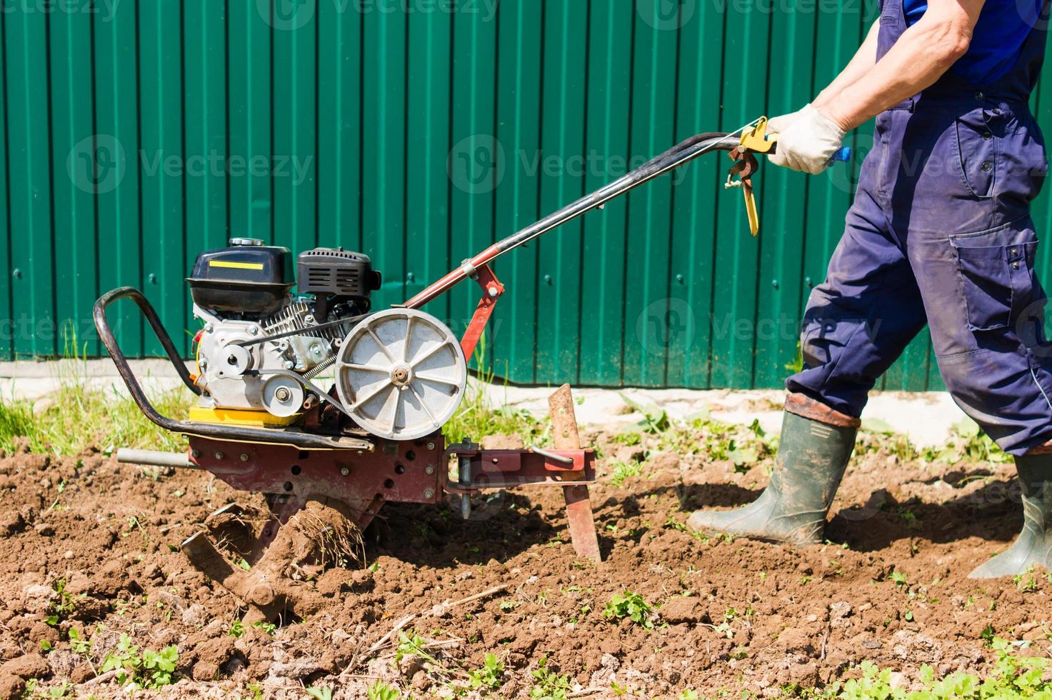 Farmer plows the land with a cultivator. Agricultural workers with